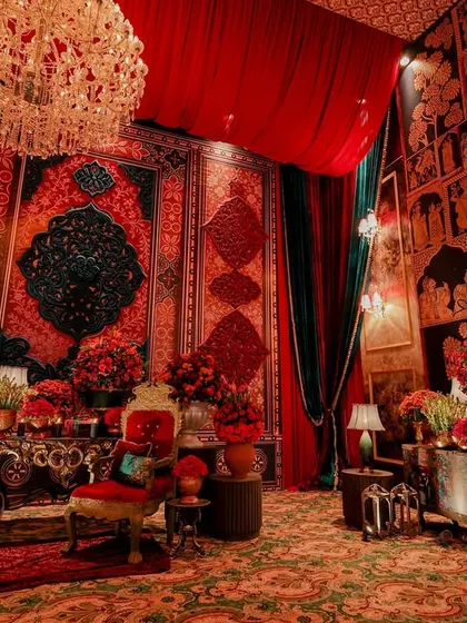 A wider view of a lounge area, showcasing walls covered in rich, patterned textiles and traditional artwork. The space is designed to feel like a chamber within a royal palace, complete with luxurious seating.