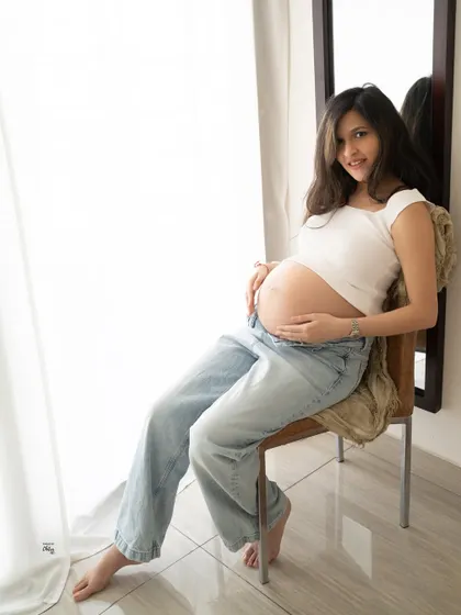 A confident and relaxed pose. This shot by the window in a casual outfit showcases a modern and comfortable approach to maternity photography.