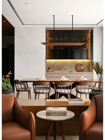 The dining area features a custom table with a sculptural metal base and elegant wooden chairs, positioned to enjoy views of the outdoors.