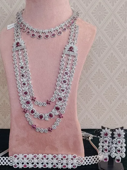A complete AD stone bridal set with ruby-colored stones, including a choker, a long necklace, earrings, and a waist belt.