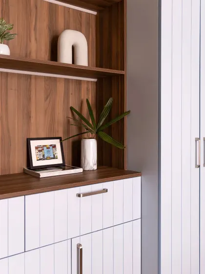 A close-up of the bookshelf, showing the warm wood-textured back panel and the clean white shelves.