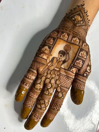 A close-up of a detailed Karwa Chauth portrait. The intricate work on the woman's attire and the surrounding frame of diyas showcases our skill in creating narrative henna art.