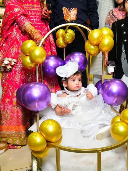 The birthday girl makes her grand entrance in a beautiful carriage decorated with purple and gold balloons, a centerpiece of her butterfly-themed party.