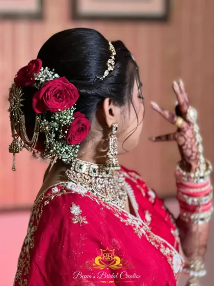 A view of the elegant bridal bun, adorned with fresh red roses and a traditional hair accessory.