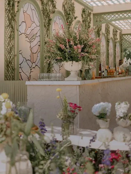 The main bar for the luncheon was set against a custom backdrop with stained-glass-effect panels and climbing ivy. A large urn of fresh flowers serves as a beautiful focal point.