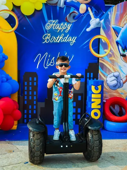 The birthday boy looking cool on a mini Segway in front of his Sonic-themed birthday backdrop.