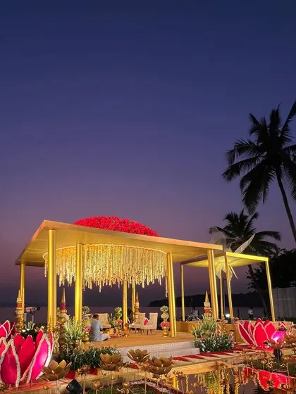 The dramatic sunset view of the 'Kamal Palace' mandap, with its bold red floral roof and glowing lotus accents creating a truly royal ambiance.
