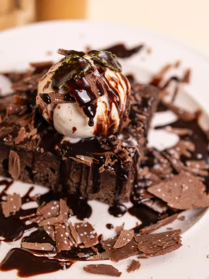 A rich, fudgy brownie topped with a scoop of vanilla ice cream and chocolate shavings. It's pure indulgence!