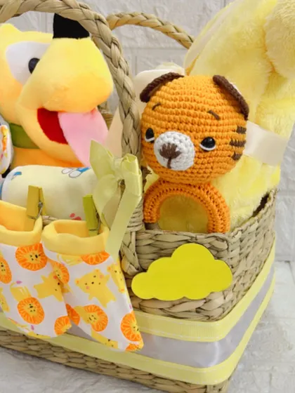 This image captures the adorable combination of the hand-knitted toy and soft booties, clipped to the side of the basket for a charming presentation.