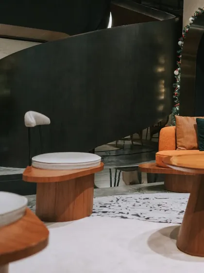 A stylish waiting area featuring custom curved wooden tables and comfortable seating. This design moves away from traditional lobby furniture to create a more relaxed and sophisticated lounge-like experience for visitors.