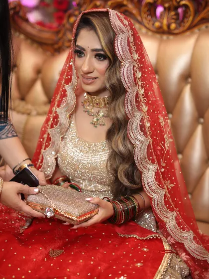 A candid shot of the bride during her engagement ceremony, holding a clutch and looking on as the event unfolds.