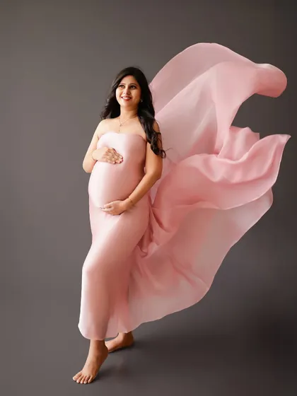 A simple yet stunning portrait with flowing fabric. The soft pink gown against a grey backdrop creates a beautiful contrast and sense of movement.