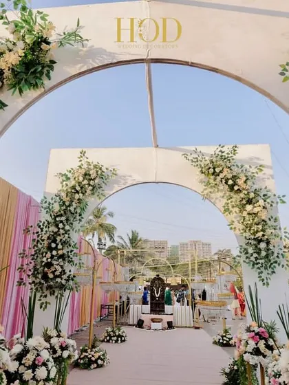 A series of nested arches adorned with white and pink florals creates a stunning and romantic entrance. This design provides a beautiful photo opportunity and a sense of depth as guests walk through.