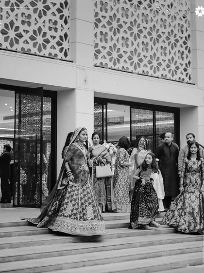 A timeless black and white photograph of the bride's arrival. We ensure our venue's architecture, with its clean lines and grand staircase, provides a classic and elegant backdrop for these significant, candid moments of your wedding day.