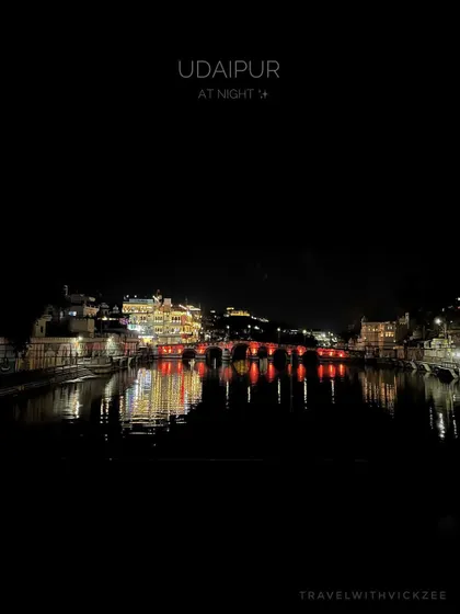Udaipur's cityscape illuminated at night, with the lights reflecting beautifully on the surface of Lake Pichola.