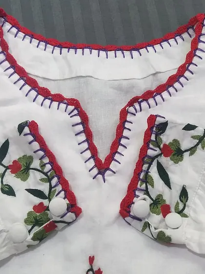 A closer look at the V-neckline, showing how the red crochet lace complements the purple embroidery stitches on the top.