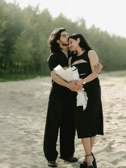 A tender moment from a beach pre-wedding shoot, as the groom-to-be kisses his partner's forehead.