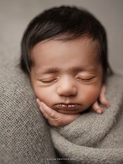 A detailed close-up of a newborn's face, with their tiny hand tucked under their chin. I love capturing these fleeting details, from the soft hair to the perfect little lips.