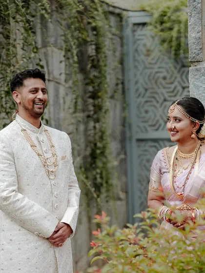 A candid moment of a couple sharing a laugh during their wedding day, captured in a natural outdoor setting.