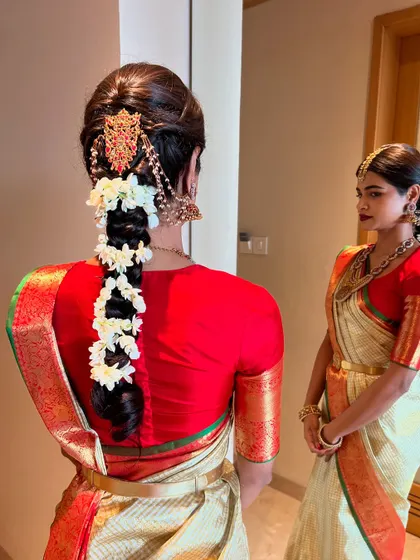 A side-by-side view of two sisters, one with a traditional floral braid and the other with a classic bun, showcasing different but complementary South Indian hairstyles.