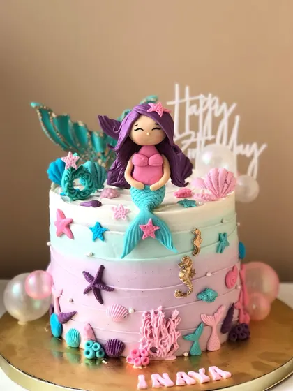A lovely mermaid cake with a handcrafted topper, bubble details, and a pastel ombre effect.