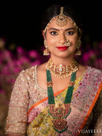 A close-up of the bride's reception look, highlighting the intricate embroidery on her blouse and her stunning emerald necklace.