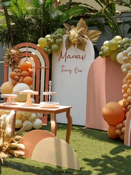 A chic and modern boho-themed party setup. The decor uses earthy tones, pampas grass, and rainbow arches for a stylish celebration.