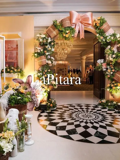 The beautiful entrance to 'Sofia's 2nd Birthday', a high-tea themed party with a soft peach and white color palette, featuring a floral arch and bunny props.
