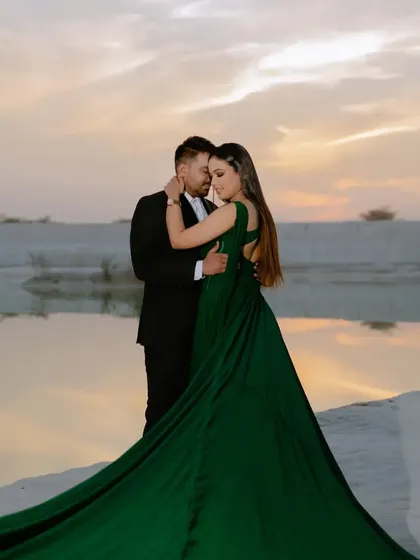 An intimate and romantic pose as the sun sets over the water. The soft, warm light and the couple's closeness make this a perfect silhouette-style pre-wedding photo.