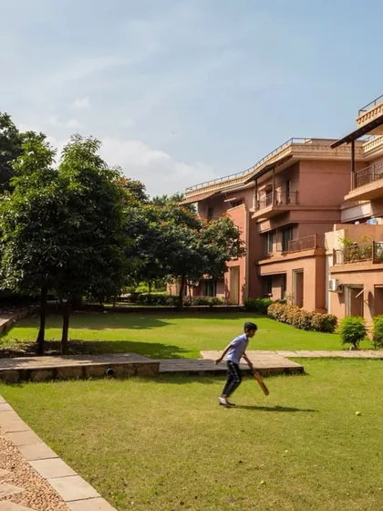 Children playing cricket in the landscaped grounds of JSW Vidyanagar, a perfect example of how we design public spaces that are truly for the people who use them.