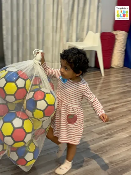 Even cleaning up is part of the learning process. This little champion is helping carry a bag of soccer balls, an activity that builds responsibility and physical strength at the same time.