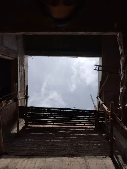 A view looking up through a large courtyard opening in a house under construction, framing the sky.