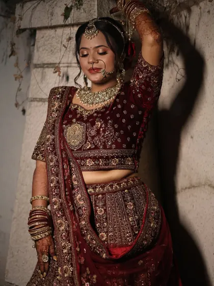 An artistic pose showcasing the intricate details of the lehenga and the bride's elegant makeup.