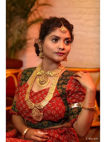 A classic pose for a traditional portrait, capturing the full splendor of the outfit and jewelry in a studio setting.