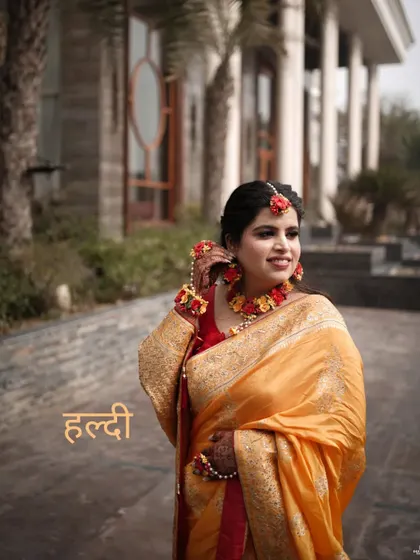 The bride in her Haldi look, with a lovely smile. The floral jewelry and the golden saree create a look of traditional elegance.