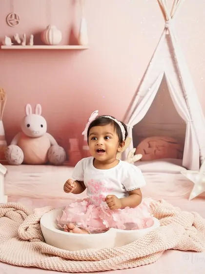 A moment of pure excitement. This toddler portrait captures a baby's joyful expression as she sits in a bowl, part of a playful and imaginative studio session.