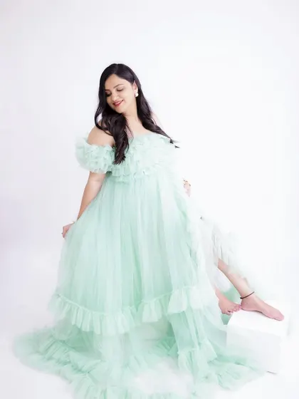 A light and airy portrait in a mint green gown. The mom-to-be's gentle smile and the soft ruffles of the dress create a sweet and delicate look.