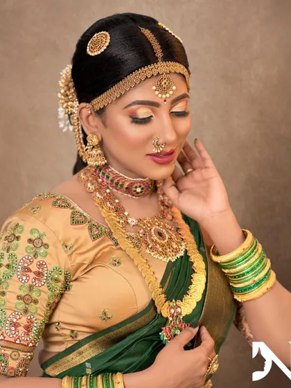 A stunning bridal look featuring a kemp jewellery set with a matha patti. The combination of gold, green, and red is a timeless choice for a South Indian bride.