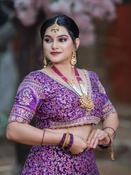 This bride looks regal in a rich purple lehenga. The look is paired with a magnificent multi-layered necklace featuring ruby and pearl details, creating a truly royal aesthetic.