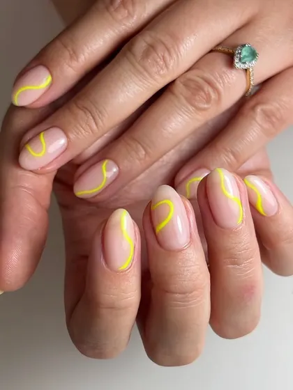 A minimalist abstract design with a single, bright yellow swirl on each nail. This is a great example of how a simple line can make a big impact.