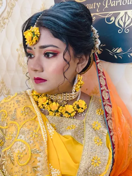 A beautiful Haldi bride with a yellow floral `maang tikka` and jewellery. The makeup is warm with peachy-pink eyeshadow and a magenta lip to add a pop of colour.