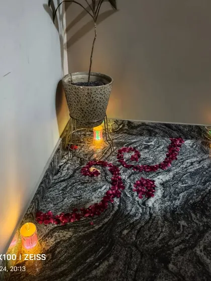 A simple 'Shubh' sign made with rose petals on a floor, surrounded by small electric diyas for Diwali.