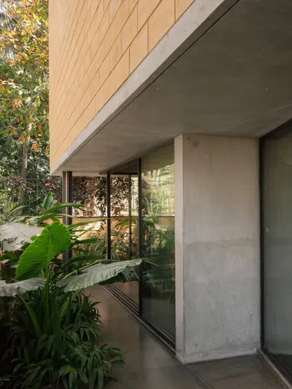 A detail of the Debris Block House showing the contrast between the textured, earth-toned debris blocks of the upper volume and the smooth, polished concrete of the ground floor.