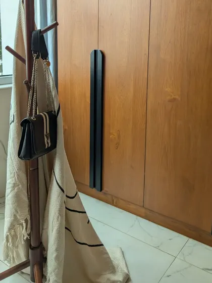 A detail shot of the long black handle on the veneer wardrobe, showcasing our focus on refined craftsmanship.