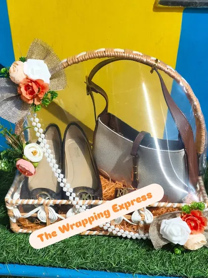 A hamper with a handbag and shoes, packed in a rustic basket and decorated with burlap flowers.