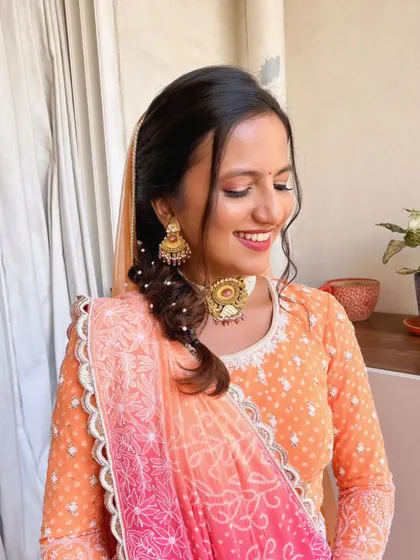 A happy, smiling client with her natural glow look. The soft makeup and braided hairstyle create a youthful and fresh appearance.