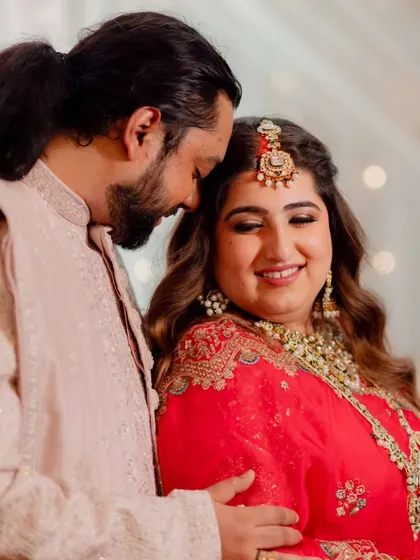 A sweet, candid moment. The soft lighting highlights her dewy makeup and the intricate details of her bridal jewelry.