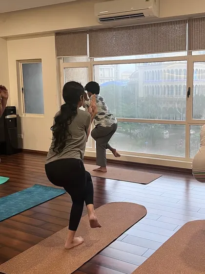 Finding balance together in a twisting chair pose. The large windows of our shala fill the room with natural light and beautiful views.