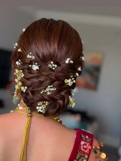 A delicate braided bun adorned with baby's breath, a classic and timeless bridal hairstyle.