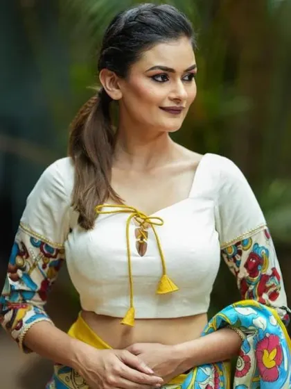 An elegant white blouse with Kalamkari printed sleeves and a tie-up detail at the front. The yellow tassels add a pop of color.